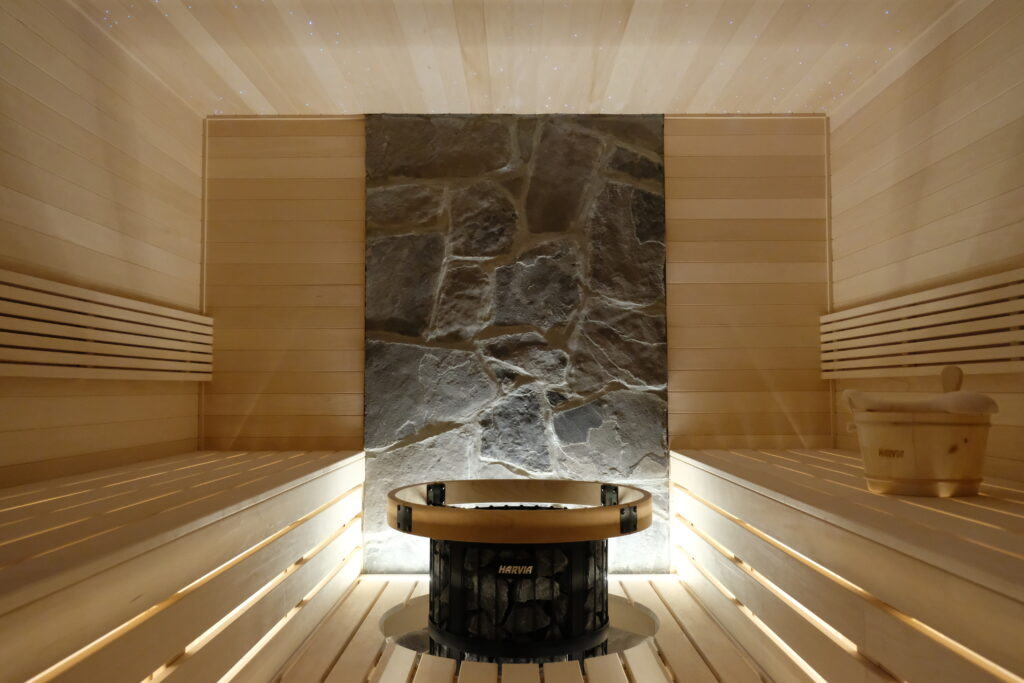 Custom aspen sauna with stone feature wall and round Harvia heater