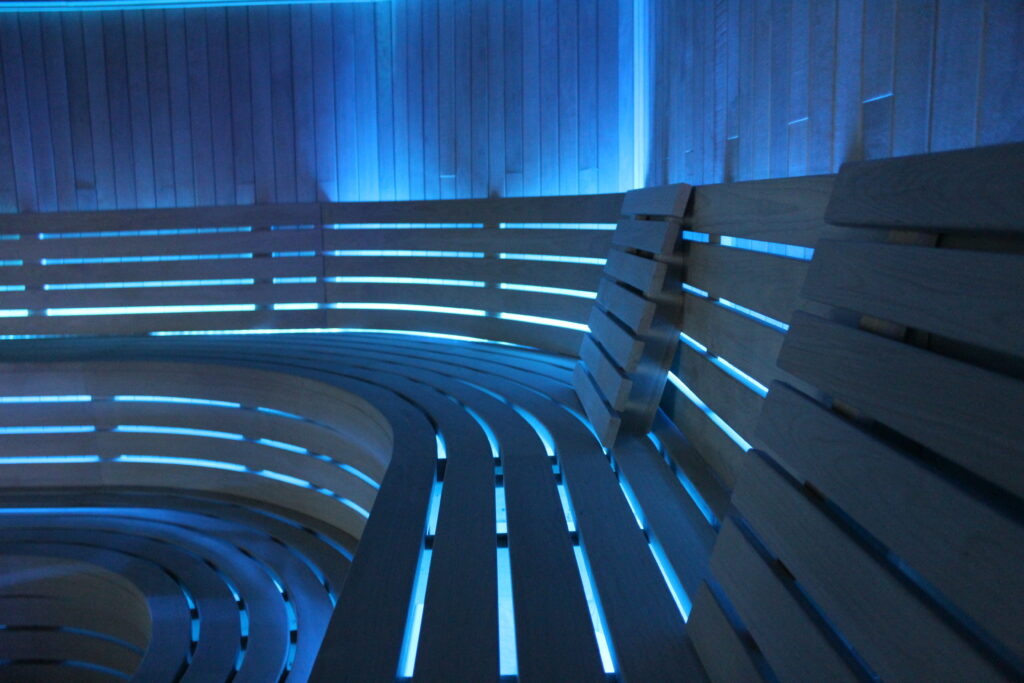 Commercial sauna with curved benches and blue ambient lighting
