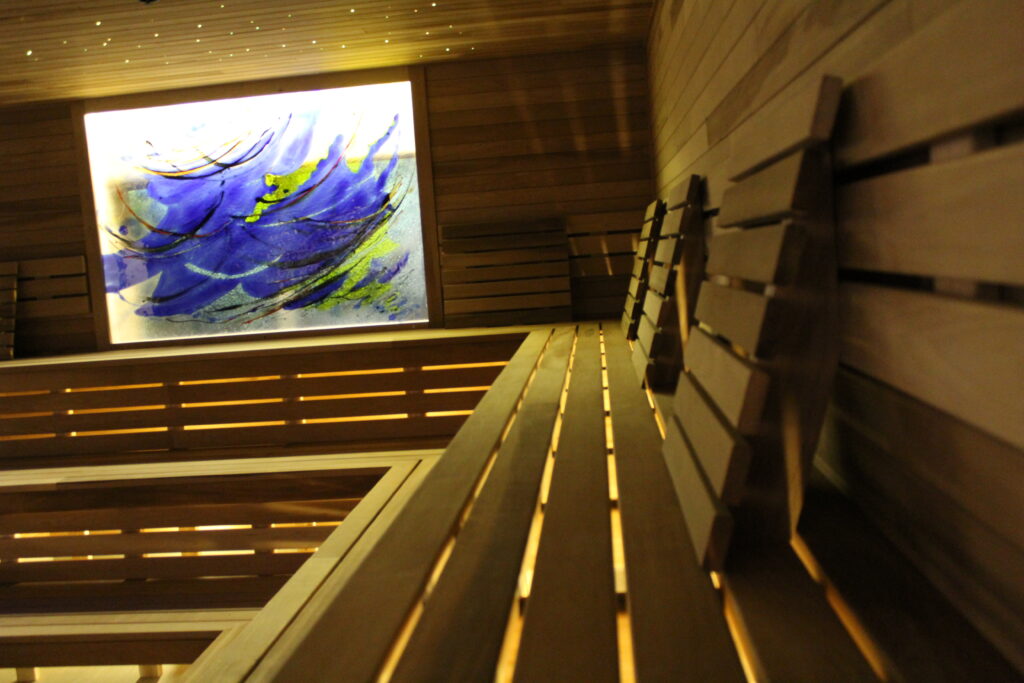Curved sauna benches with backlit art panel