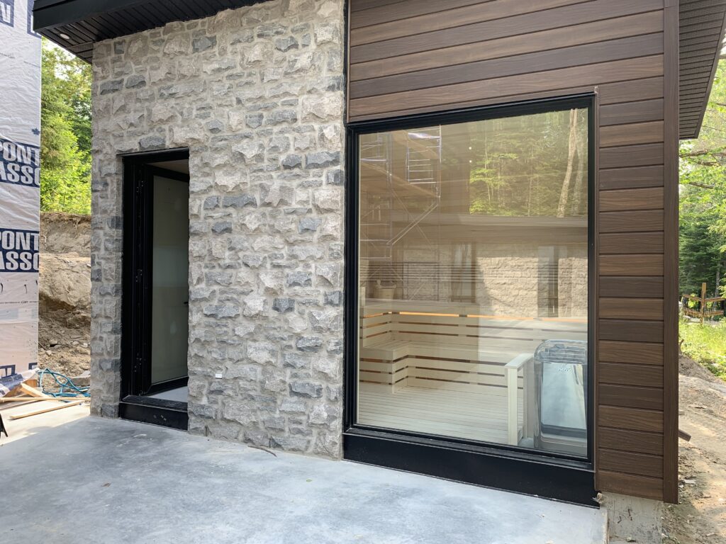 Custom outdoor sauna with stone facade and large glass window