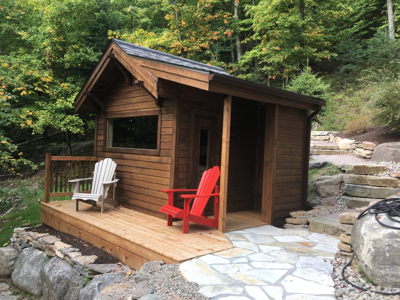 Custom cedar outdoor sauna with a porch and Adirondack chairs