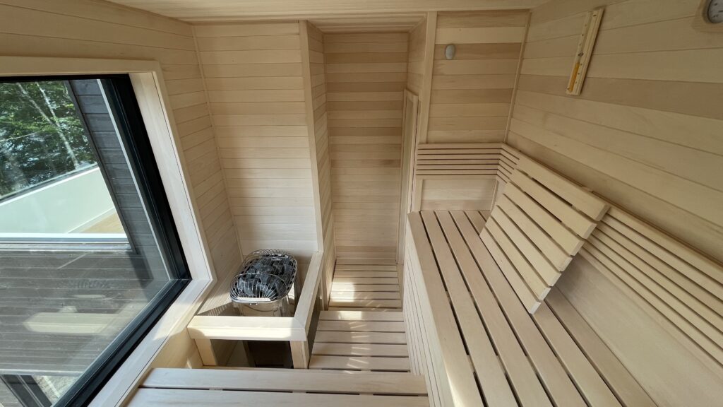 Wide view of an outdoor sauna interior with benches and heater